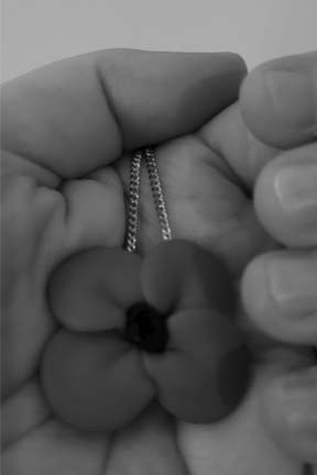 Hand holds a poppy on a chain.